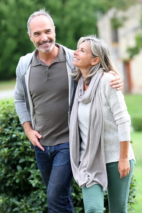 Bioidentical-Hormone-Therapy-Treatment A mature couple in gray toned clothes and jeans walk happily outside, happy with their successful bioidentical hormone treatments from Kane Lai, MD in Dallas-Fort Worth Metroplex.