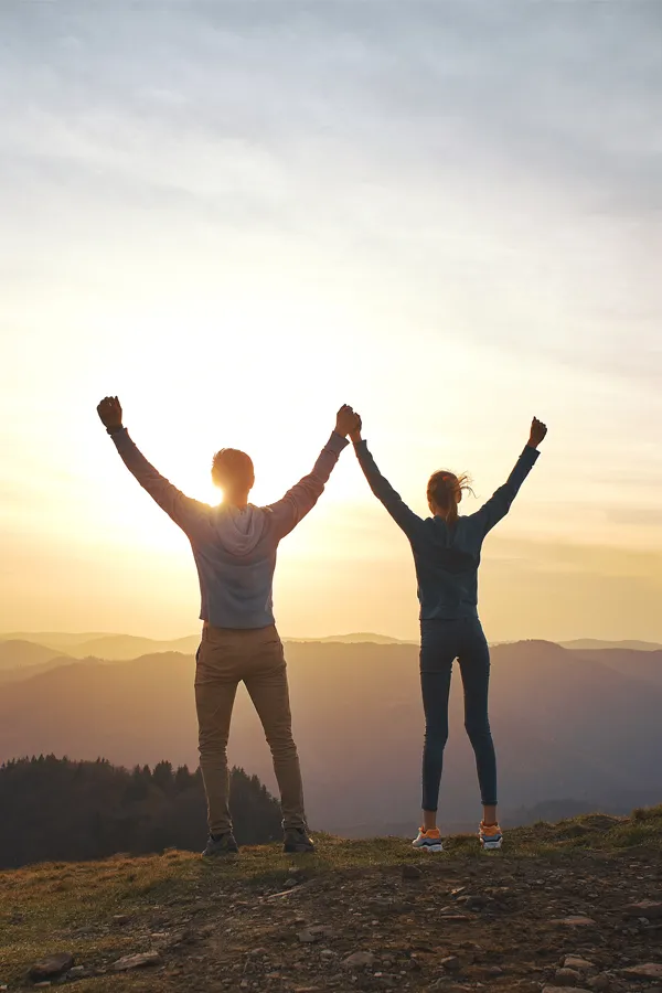 DHEA-Hormone-Treatment A couple raises their hands in triumph on a mountaintop. Get DHEA hormone therapy from Kane Lai, MD in Dallas-Fort Worth Metroplex.