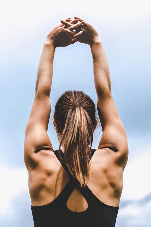 GLP-1-Weight-Loss-Injections-Treatment A toned woman seen from behind stretching her arms into the air. Get GLP-1 Weight Loss Injections from Kane Lai, MD in Dallas.