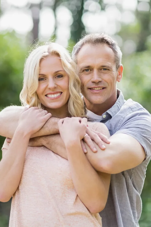 HGH-Hormone-Treatment A middle-aged couple embrace outdoors on a sunny day. Get HGH hormone therapy from Kane Lai, MD in Dallas-Fort Worth Metroplex.