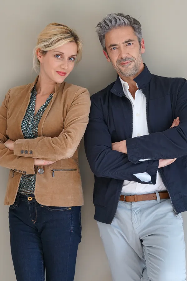 Hyperthyroidism-Treatment A middle-aged couple stand against a wall smiling with folded arms. Get hyperthyroidism treatment from Kane Lai, MD in Dallas-Fort Worth Metroplex.