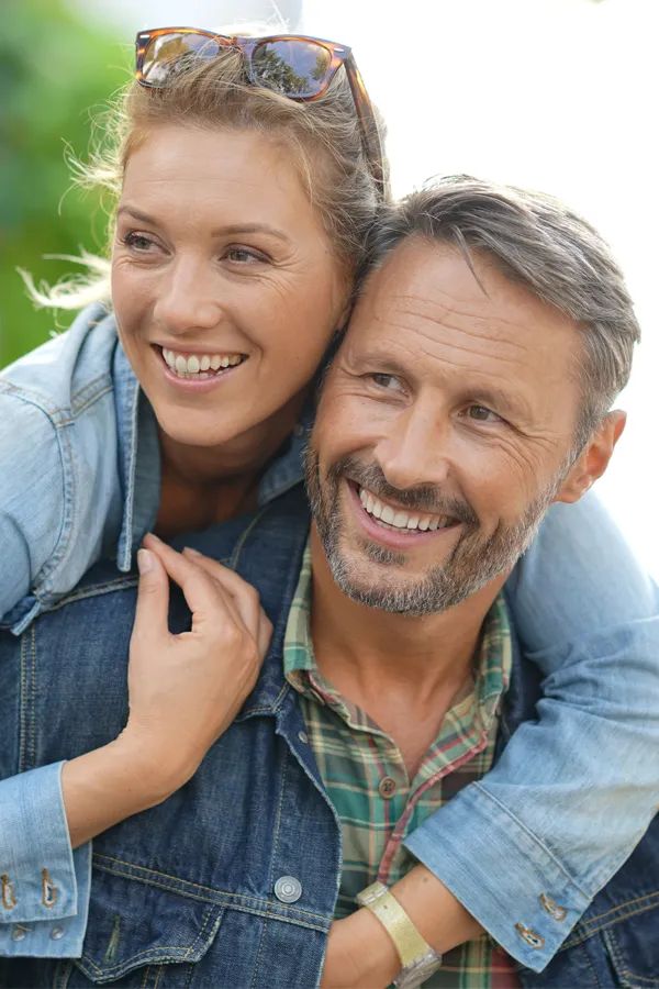 Hypogonadism-Treatment A couple in denim jackets embrace playfully outdoors. Get hypogonadism treatment from Kane Lai, MD in Dallas-Fort Worth Metroplex.