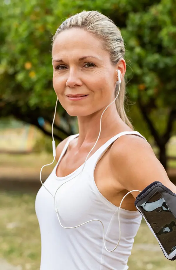 Insulin-Resistance-Treaatment A fit middle aged woman wearing earphones and a tank top smiles after a run. Get insulin resistance treatment from Kane Lai, MD in Dallas-Fort Worth Metroplex.
