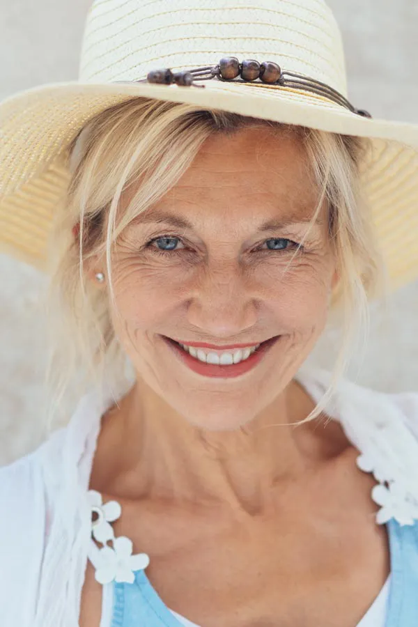 Menopause-Treatment A beautiful, smiling older woman with blonde hair and a sunhat, happy with menopause treatment from Kane Lai, MD in Dallas-Fort Worth Metroplex.