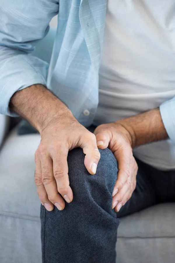 Osteoporosis-Pain A close-up of a man holding his knee while experiencing pain from osteoporosis. Get osteoporosis treatment from Kane Lai, MD in Dallas-Fort Worth Metroplex.