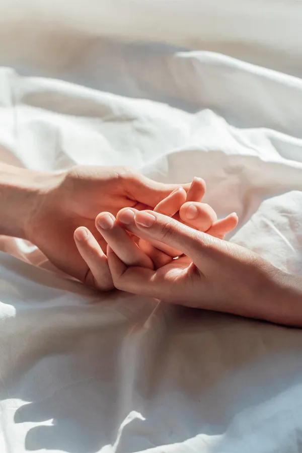 PT141-for-Women-Treatment A close up of a man and woman's hands lightly clasping on a bedsheet, representing successful PT141 sexual wellness treatment for women from Kane Lai, MD in Dallas-Fort Worth Metroplex.