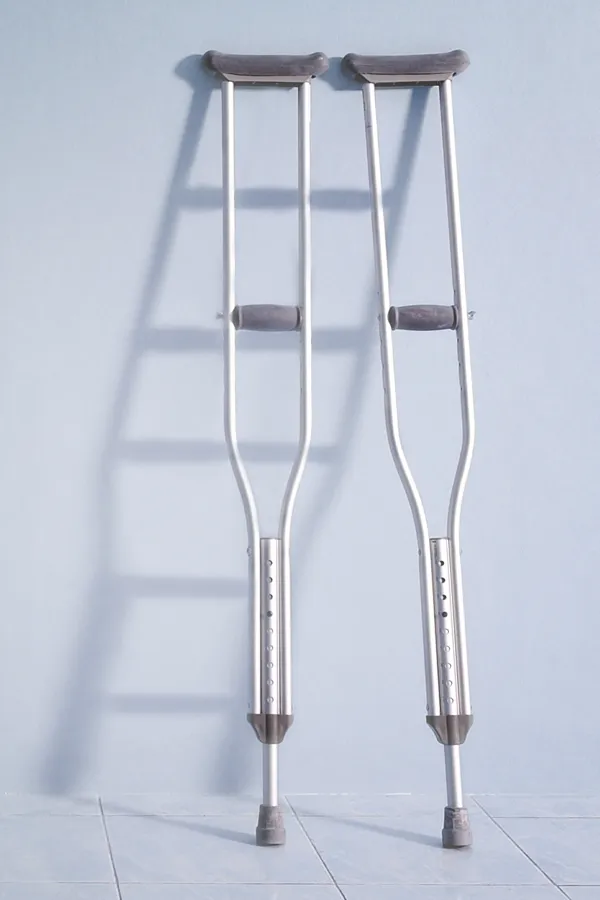 Peptides-for-Healing-and-Recovery-Treatment A pair of crutches rest against a gray wall, representing peptide therapy for healing and recovery from Kane Lai, MD in Dallas-Fort Worth Metroplex.