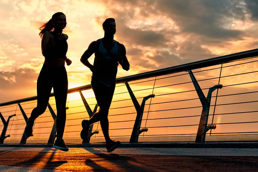 Performance-Enhancing-Peptides-Doctor A couple jogging on a bridge at sunrise, representing performance enhancing peptide therapy from Kane Lai, MD in Dallas-Fort Worth Metroplex.
