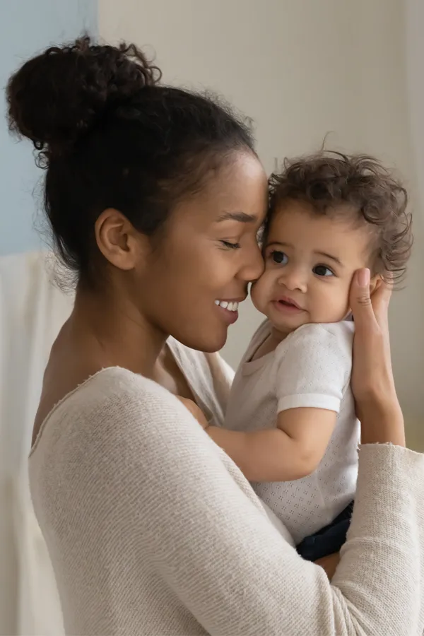 Postpartum-Hormone-Imbalance-Treatment A black woman happily touches her forehead to her infant's head. Get treatment for postpartum hormone imbalance from Kane Lai, MD in Dallas-Fort Worth Metroplex.