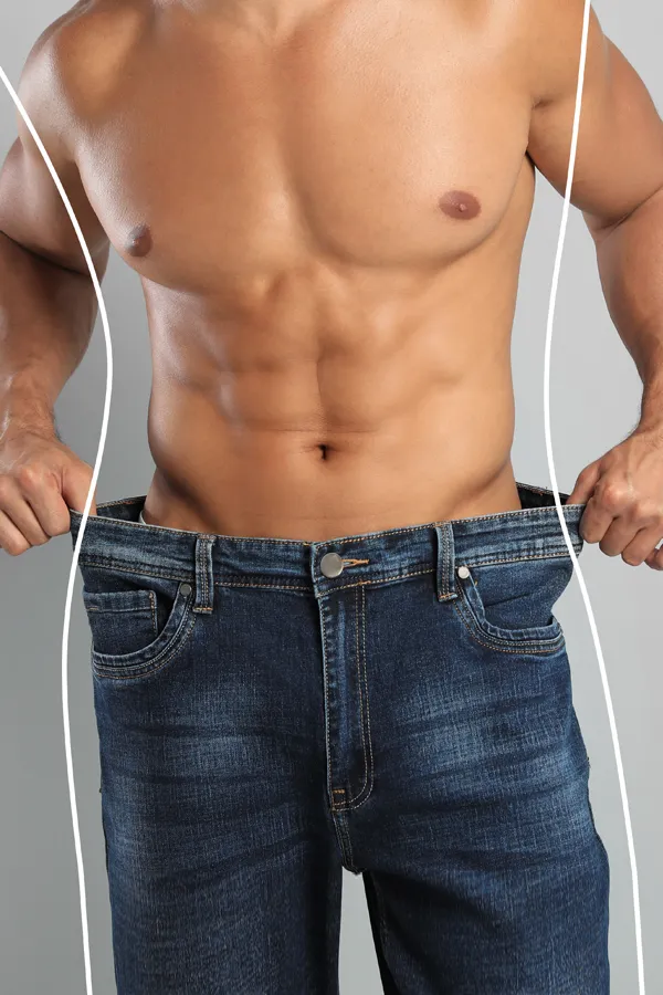 Semaglutide-Weight-Loss-Treatment A strong shirtless man in jeans holds the waistlines of his too-big jeans to show the success of semaglutide weight loss from Kane Lai, MD in Dallas.