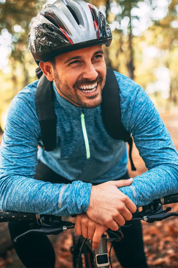 Testosterone-Low-T-Solutions-Treatment A middle-aged man on a trail in cycling clothes is smiling and leaning on his bike's handlebars. Get testosterone for Low T from Kane Lai, MD in Dallas-Fort Worth Metroplex.